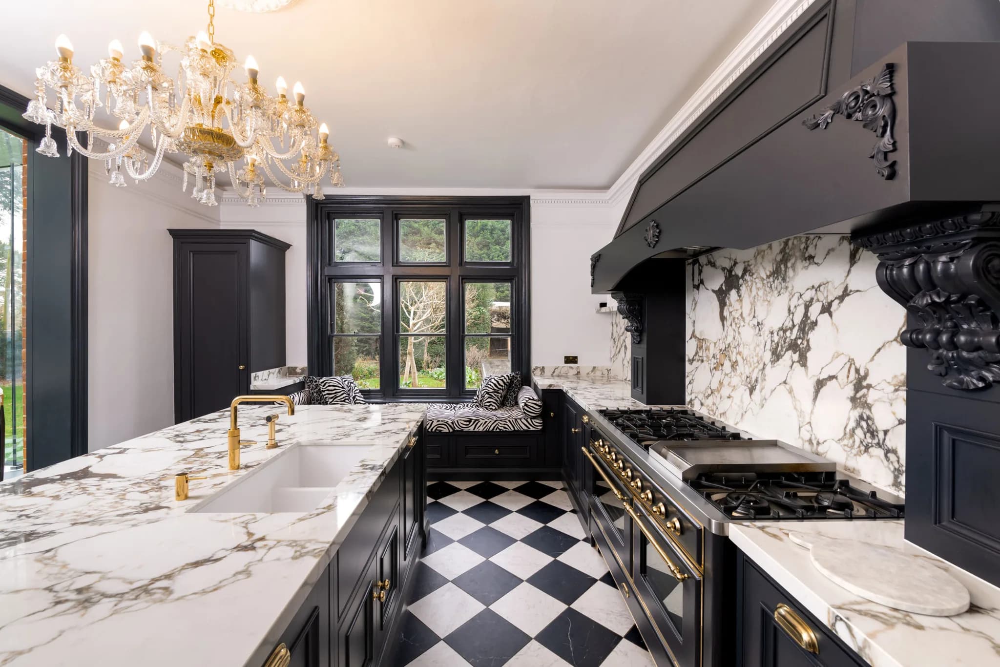 Black moulded in-frame kitchen with marble worktops, a range hood and a crystal chandelier in Sawbridgeworth
